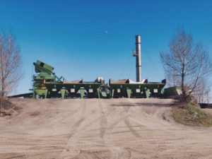 Impianto industriale con silos numerati e camino, cielo azzurro.