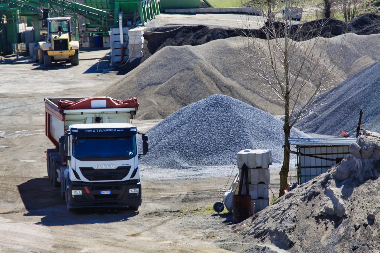 Camion e cumuli di ghiaia in un cantiere.