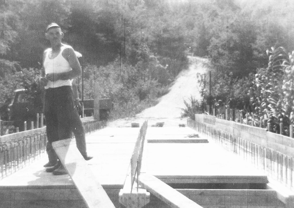 Uomo su un ponte in costruzione, area boschiva.