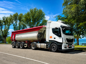 Camion bianco con rimorchio rosso parcheggiato vicino alberi.